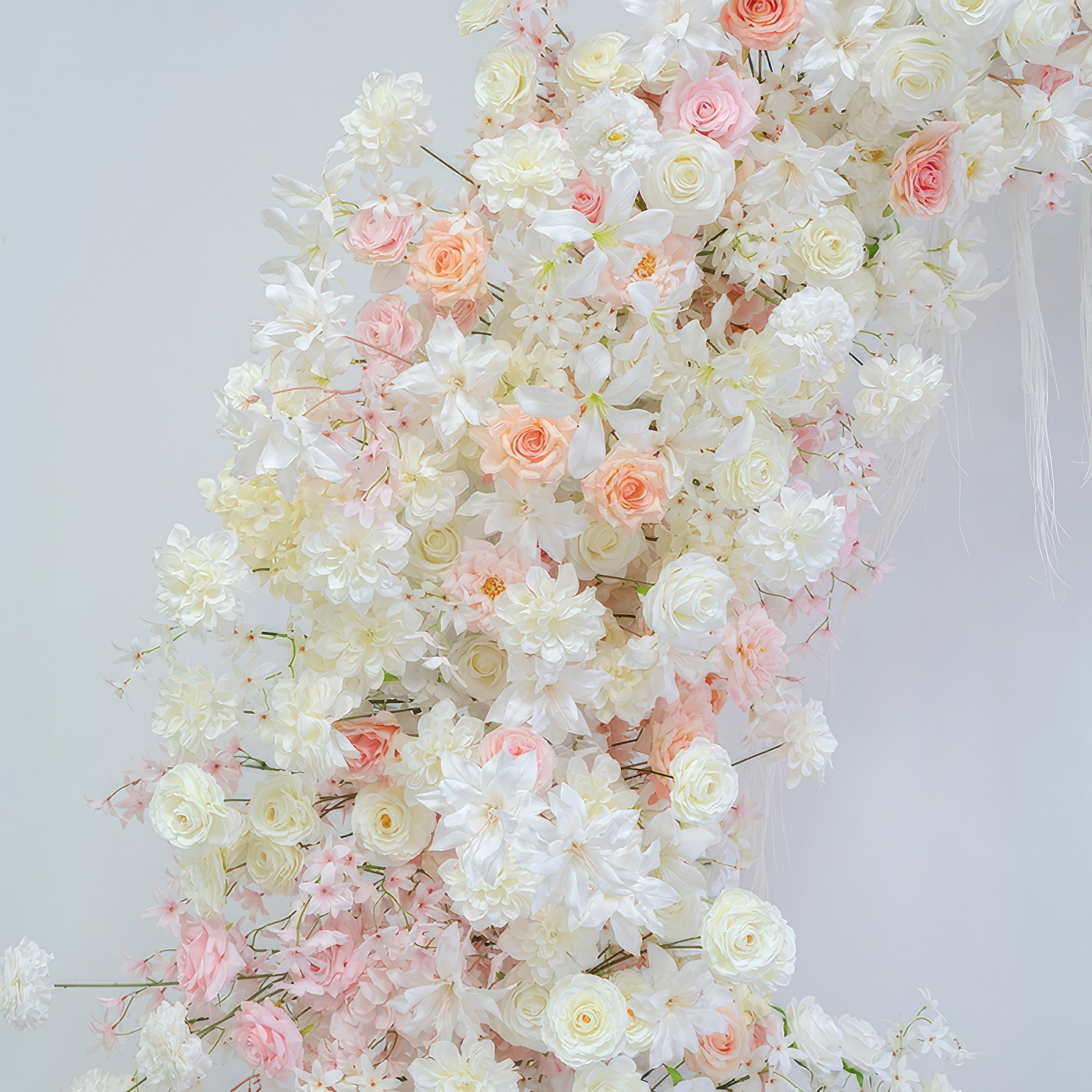 This image presents an artificial flower arrangement with roses, hydrangeas and other blossoms. Colors are soft white, light pink and peach. The style is romantic and elegant, exuding a gentle charm. 