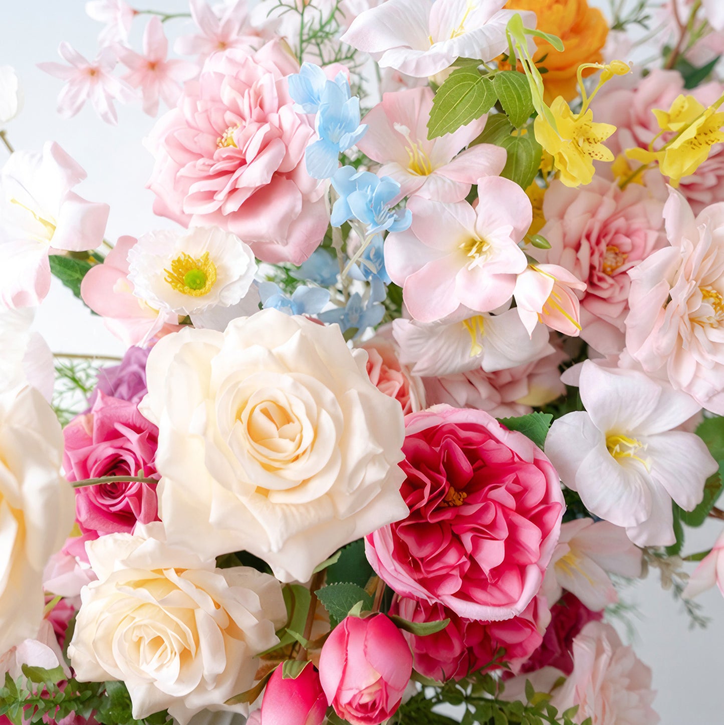 This close - up reveals a charming blend of artificial flowers. Soft pastel hues dominate, with pink, white, and light blue blooms creating a gentle backdrop. Vivid red and yellow flowers add pops of color. Roses and other delicate blossoms are combined, giving it a sweet, romantic style. 