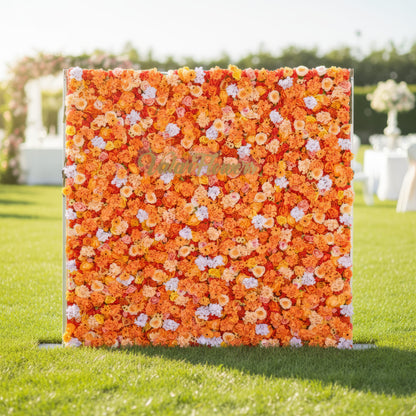 This image showcases a vibrant floral backdrop by Valar Flowers, set outdoors on a lush lawn. It features a dense arrangement of artificial flowers in warm shades of orange, peach, and hints of pink. The textured display exudes energy, with the brand’s name integrated, perfect for adding a bold, nature-inspired element to outdoor events.