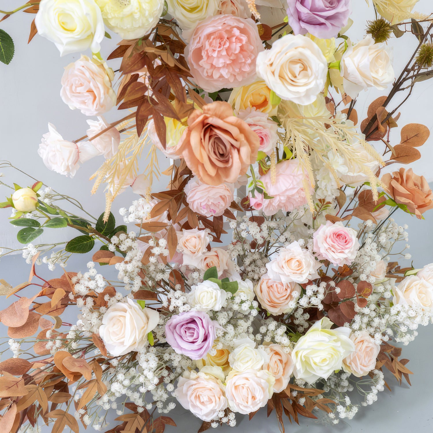 This artificial flower arrangement features a charming mix of roses in various pastel hues such as pink, peach, lavender, and cream. Accented with brown - tinged leaves and small white filler flowers, it radiates a warm, soft, and romantic vibe. 
