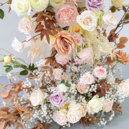 This artificial flower arrangement features a charming mix of roses in various pastel hues such as pink, peach, lavender, and cream. Accented with brown - tinged leaves and small white filler flowers, it radiates a warm, soft, and romantic vibe. 