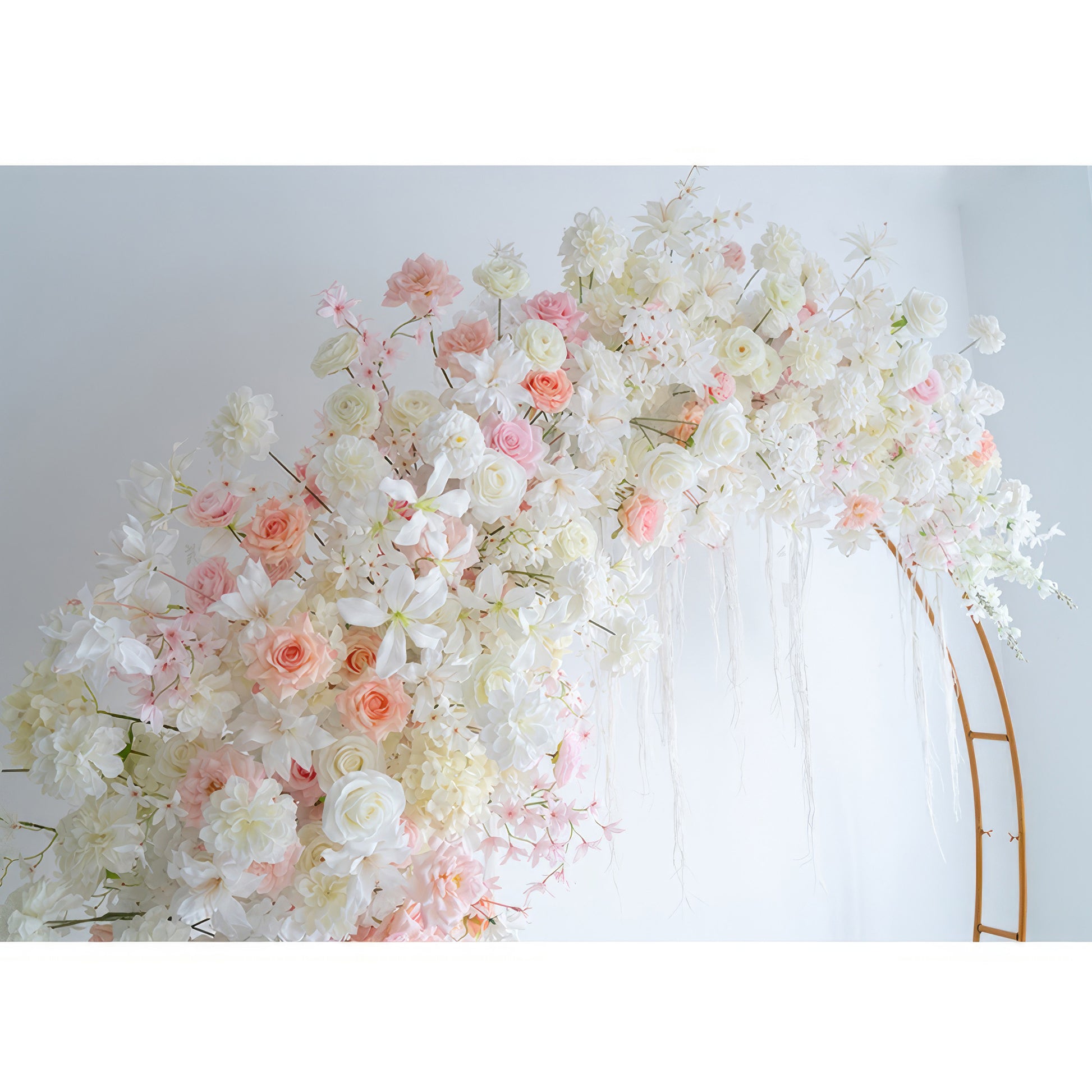 This image displays a circular floral arch made of artificial flowers. It features roses and other blossoms in a palette of white, light pink, and peach. The style is soft, romantic, and perfect for a wedding - like setting. 