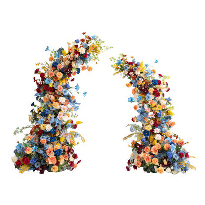 This image shows a pair of floral arches brimming with artificial flowers. Colors include deep red, bright blue, orange, and yellow. Styles range from roses to daisies, creating a vivid, celebratory style. 