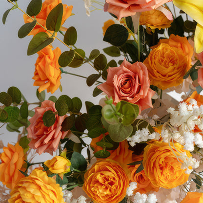 This is a vibrant flower arrangement predominantly featuring orange and peach - colored roses. Interspersed among the roses are small white blooms, likely baby&