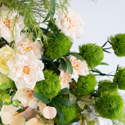 The image features artificial flowers in soft pastel pink, vivid green, and light beige. There are large, ruffled pink blooms and spherical green foliage. The style is fresh, natural, and exudes a romantic charm. 