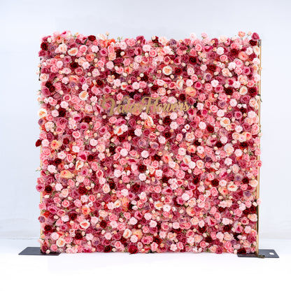 A square floral wall backdrop covered in dense pink, red, and peach faux flowers, with a gold script logo reading 'Blush Florals' across the center, photographed against a clean white background.