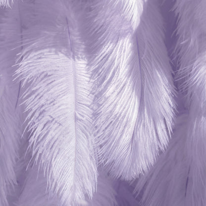 This close-up showcases soft, layered lavender ostrich feathers, with a gradient of pale lilac to deeper lavender hues. Sunlight catches the fine filaments, creating bright, almost-white highlights that contrast with soft, muted purple shadows. The feathery texture feels ethereal, with subtle tonal variations enhancing depth—merging dreamy pastels and gentle light to evoke a lush, romantic, and whimsical atmosphere.