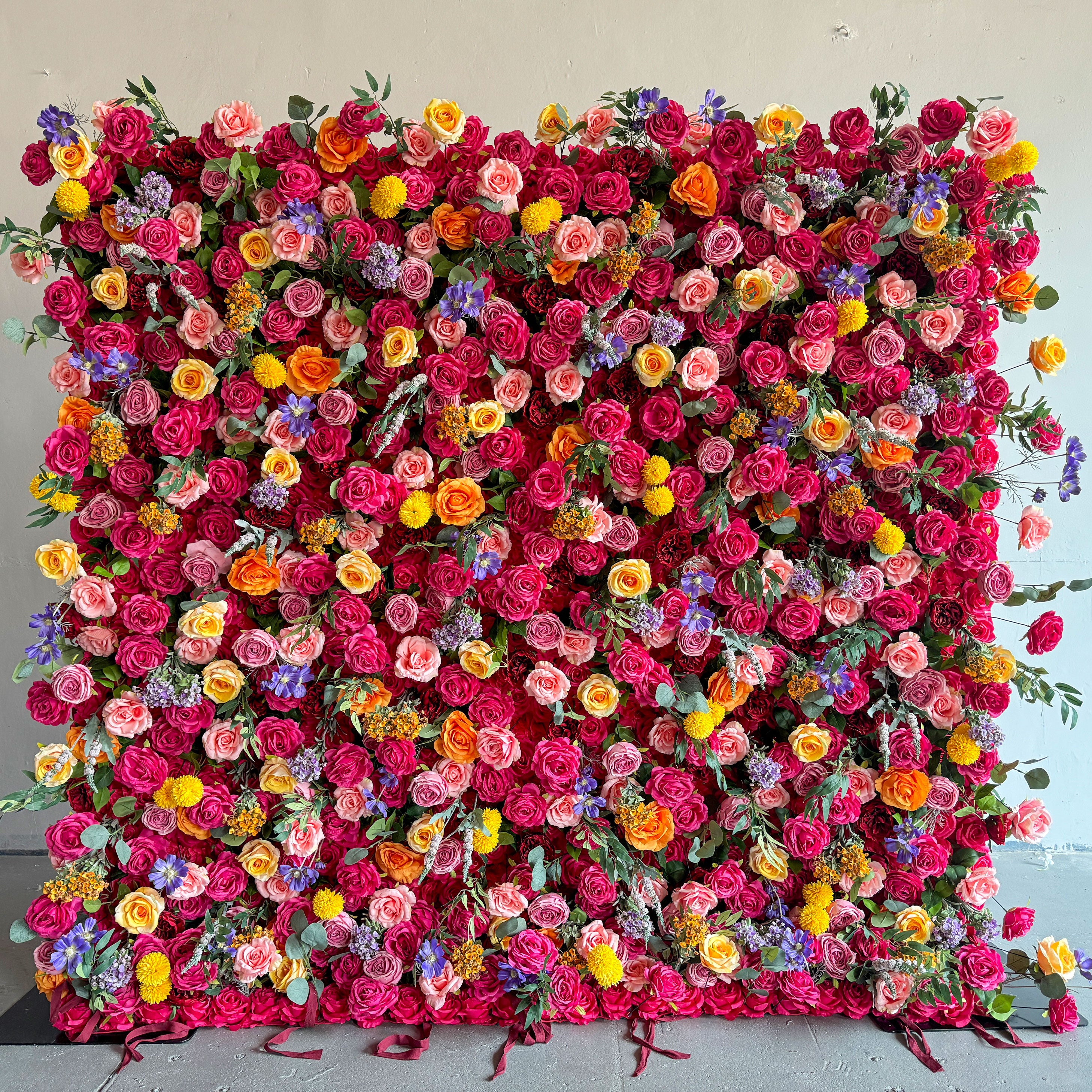 This artificial flower wall is a stunning piece. It is densely packed with a variety of colorful flowers, including vibrant roses, delicate lilies, and charming daisies. The flowers are complemented by lush green leaves, creating a rich and lively appearance. It is perfect for weddings, parties, or any event, providing a beautiful and eye - catching backdrop.
