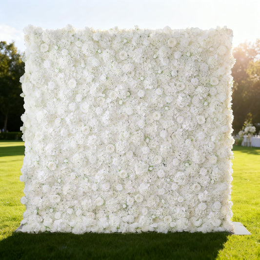 This image showcases a large, square floral wall outdoors on a lush green lawn. It's densely covered with pure white flowers, creating a clean, elegant, and serene display. Bathed in sunlight, with trees and a bright sky in the background, the scene exudes a sense of purity and natural beauty. From the brand 'Valar Flowers', this floral wall is perfect for decorative purposes in events or as a captivating backdrop.