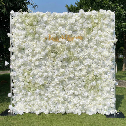 This outdoor floral backdrop (set on lush green grass, framed by trees) is a dense, immaculate wall of white roses and delicate baby’s breath, creating a soft, ethereal texture. A polished, cursive "VALAR Flowers" gold sign anchors the center, contrasting vividly with the pure white blooms. The luminous, elegant display exudes timeless romance, perfect for weddings, upscale events, or photo setups seeking a classic, pristine aesthetic.