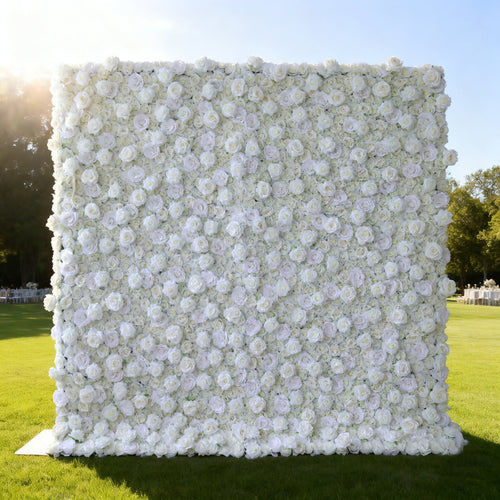 This image features a large, square floral wall outdoors on a lush green lawn. It's densely covered with pure white flowers, creating a clean, elegant, and serene display. Bathed in sunlight, with trees and event - like setups in the background, the scene exudes a sense of purity, grace, and natural beauty, perfect for decorative purposes in special events or as a captivating backdrop.