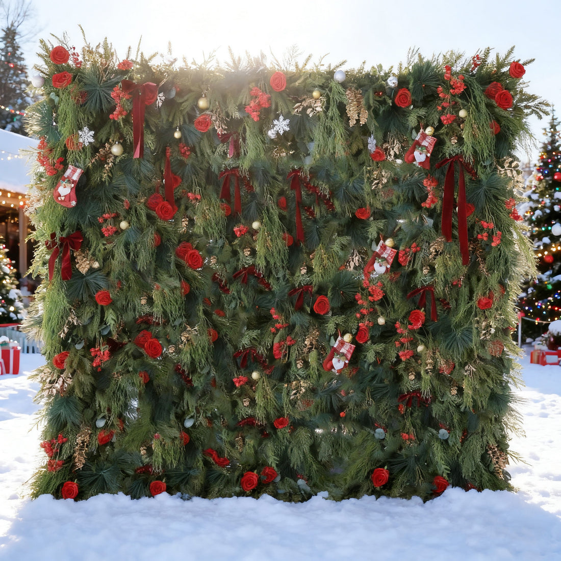 This image features a large, festive Christmas - themed floral wall. Adorned with lush green foliage, vibrant red roses, and Christmas decorations like stockings, snowflakes, and baubles, it&