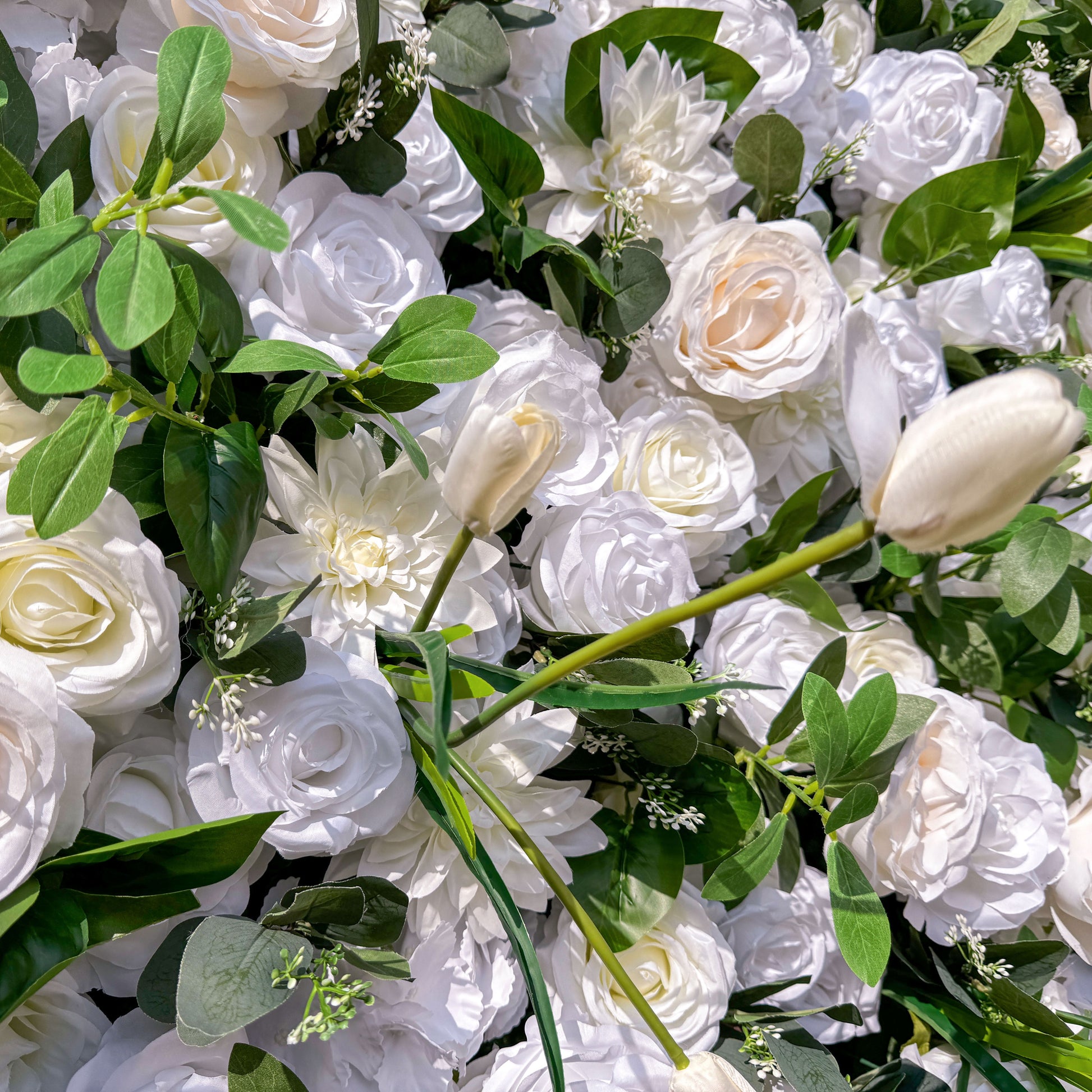 This photo features a dense arrangement of white roses, complemented by white tulips and lush green foliage. The blooms create a serene and elegant display. Ideal for events like a “Snow - White” wedding or a refined garden reception, it exudes a sense of purity and sophistication, perfect for upscale and graceful celebrations. 