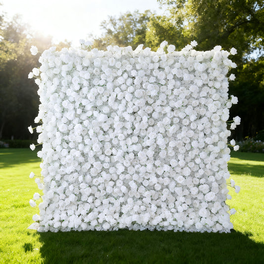 This image showcases a large, square floral wall from the brand 'Valar Flowers' outdoors on a lush green lawn. It's densely covered with pure white flowers, creating a clean, elegant, and serene display. Bathed in sunlight, with trees and a bright sky in the background, the scene exudes a sense of purity and natural beauty. This floral wall is perfect for decorative purposes in events or as a captivating backdrop, highlighting the brand's focus on exquisite floral arrangements.