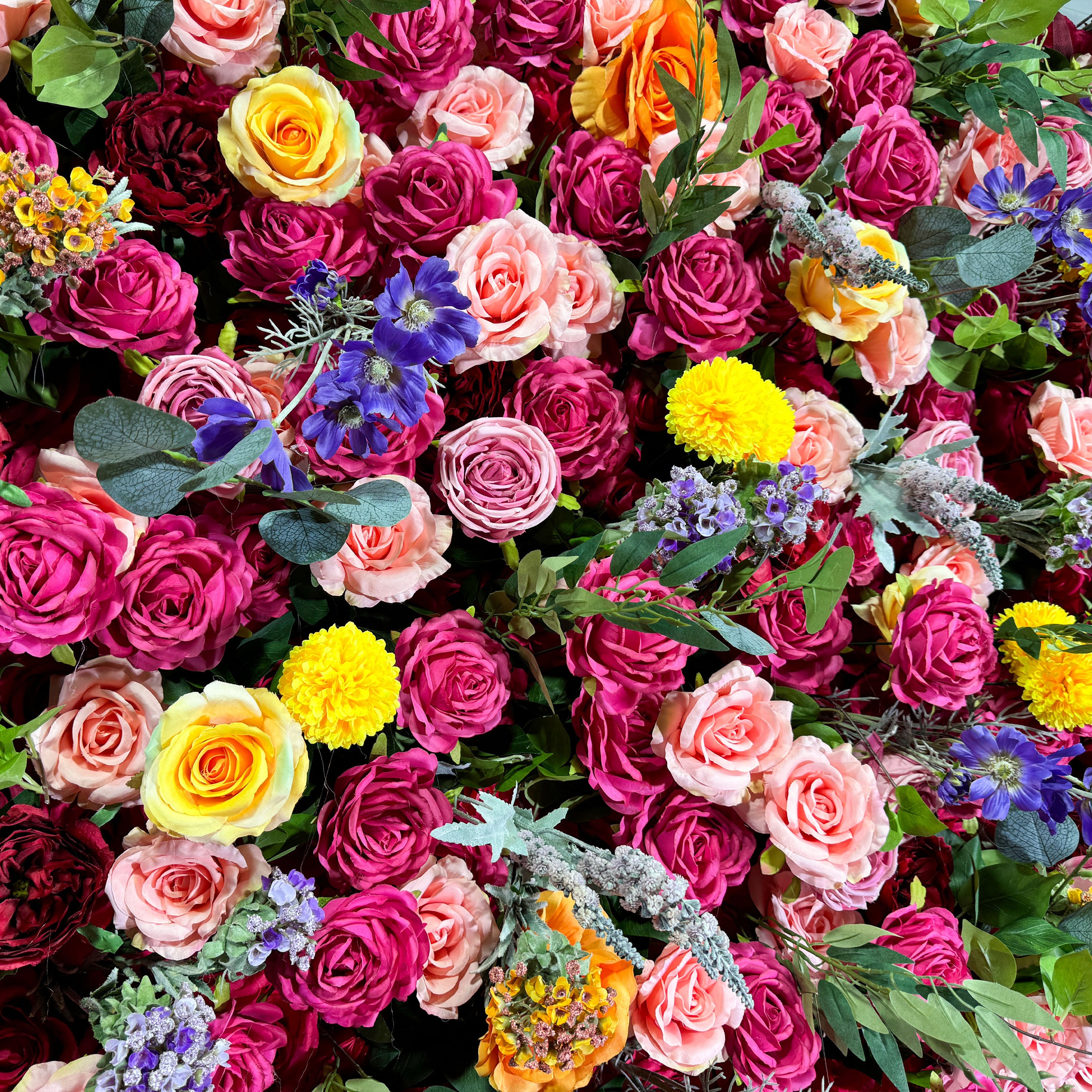 This artificial flower wall is a vibrant and eye - catching decoration. It is densely packed with a rich variety of colorful flowers, including roses, daisies, and other blooms in shades of pink, yellow, purple, and blue. The flowers are complemented by lush green leaves, creating a lush and opulent appearance. It is perfect for adding a festive and romantic atmosphere to events.