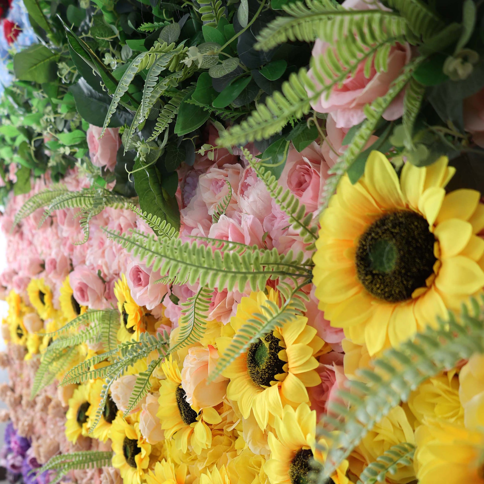 ValarFlowers' floral arrangement features vibrant yellow sunflowers, soft - pink roses, and green ferns, creating a lively and colorful display.