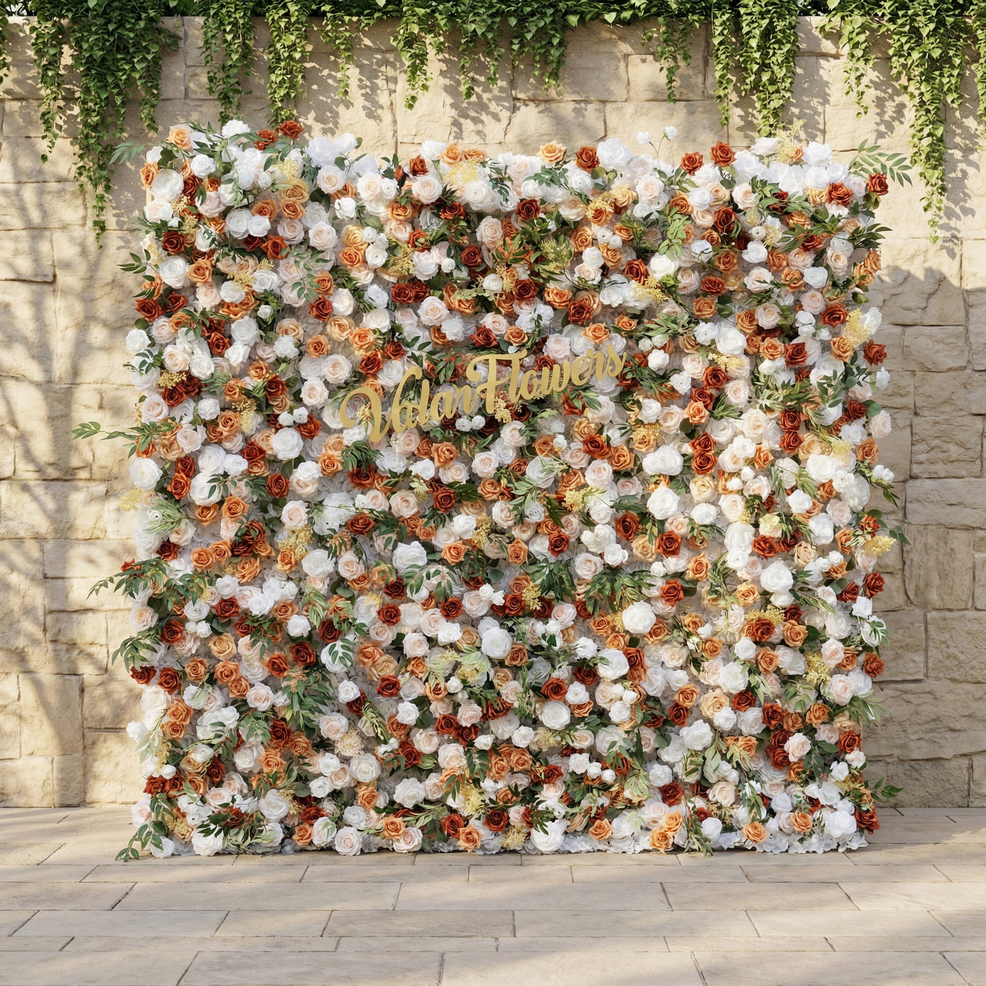 This is ValarFlowers’ premium terracotta & cream artificial flower wall backdrop, set against a sunlit stone wall with trailing ivy. It features a lush, dense arrangement of lifelike blooms: burnt orange roses, creamy white peonies, blush pink roses, and vibrant green foliage. This warm, timeless, reusable floral display creates an elegant, romantic focal point ideal for rustic weddings, fall events, photo booths, and luxury outdoor decor.