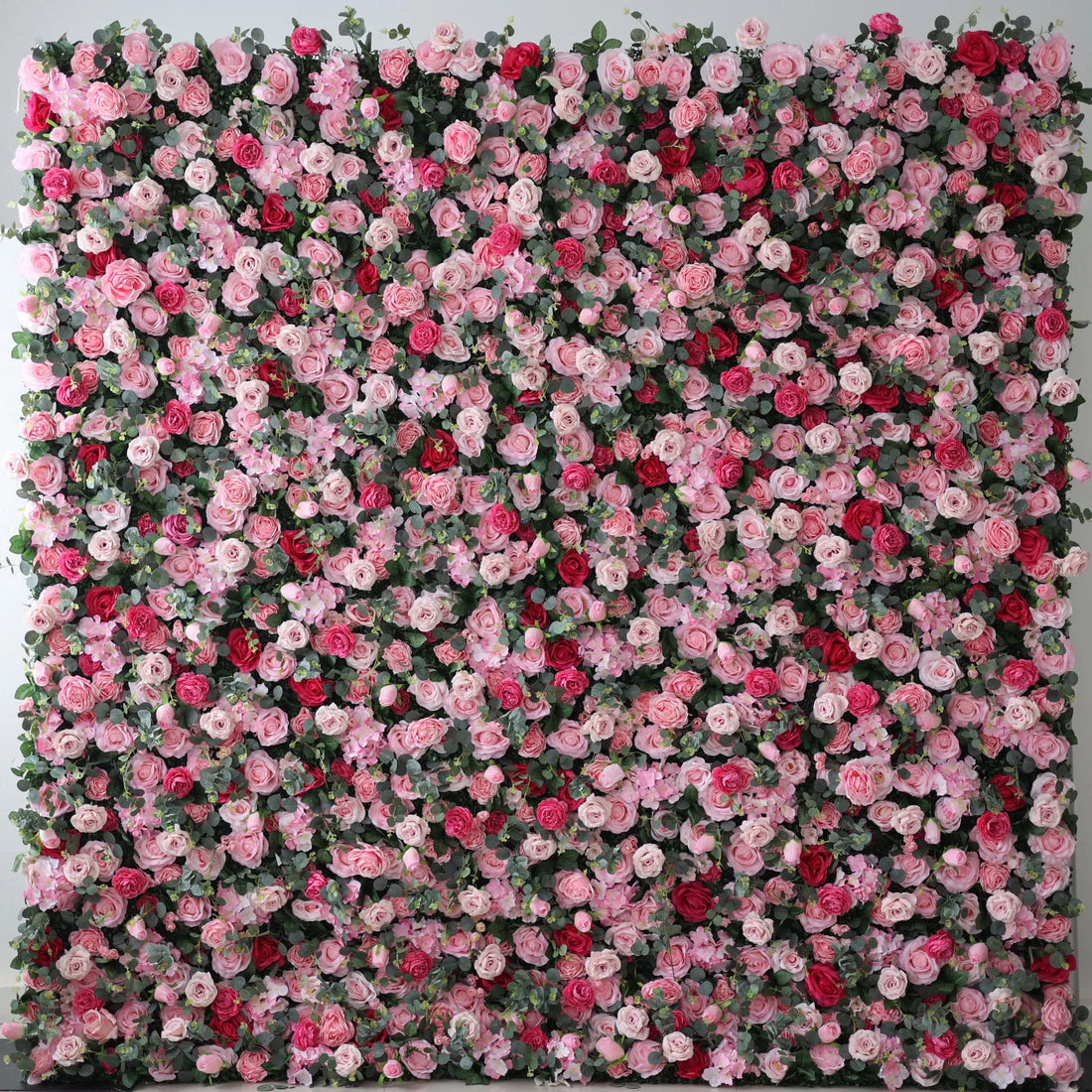A large artificial flower wall bursts with a vibrant mix of pink, light pink, and red roses, interspersed with green foliage. The dense, layered blooms create a lush, romantic, and eye - catching backdrop, perfect for adding a touch of elegance and charm to events or spaces.
