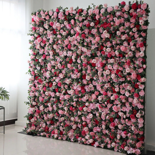 Valar Flowers' Artificial Fabric Flower Wall: Blooming Bliss. A large artificial flower wall bursts with a vibrant mix of pink, light pink, and red roses, interspersed with green foliage. The dense, layered blooms create a lush, romantic, and eye - catching backdrop, perfect for adding a touch of elegance and charm to events or spaces. 