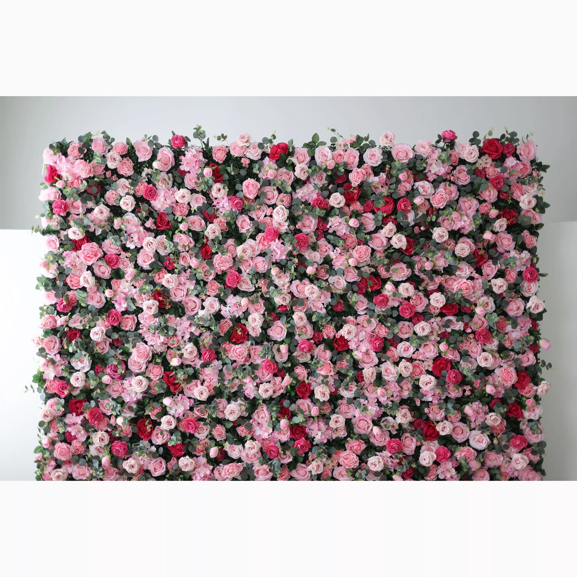 A lush artificial flower wall showcases a vibrant mix of pink, light pink, and red roses, interspersed with green foliage. The dense, layered blooms create a romantic, eye - catching backdrop, perfect for adding elegance to events or decor. 
