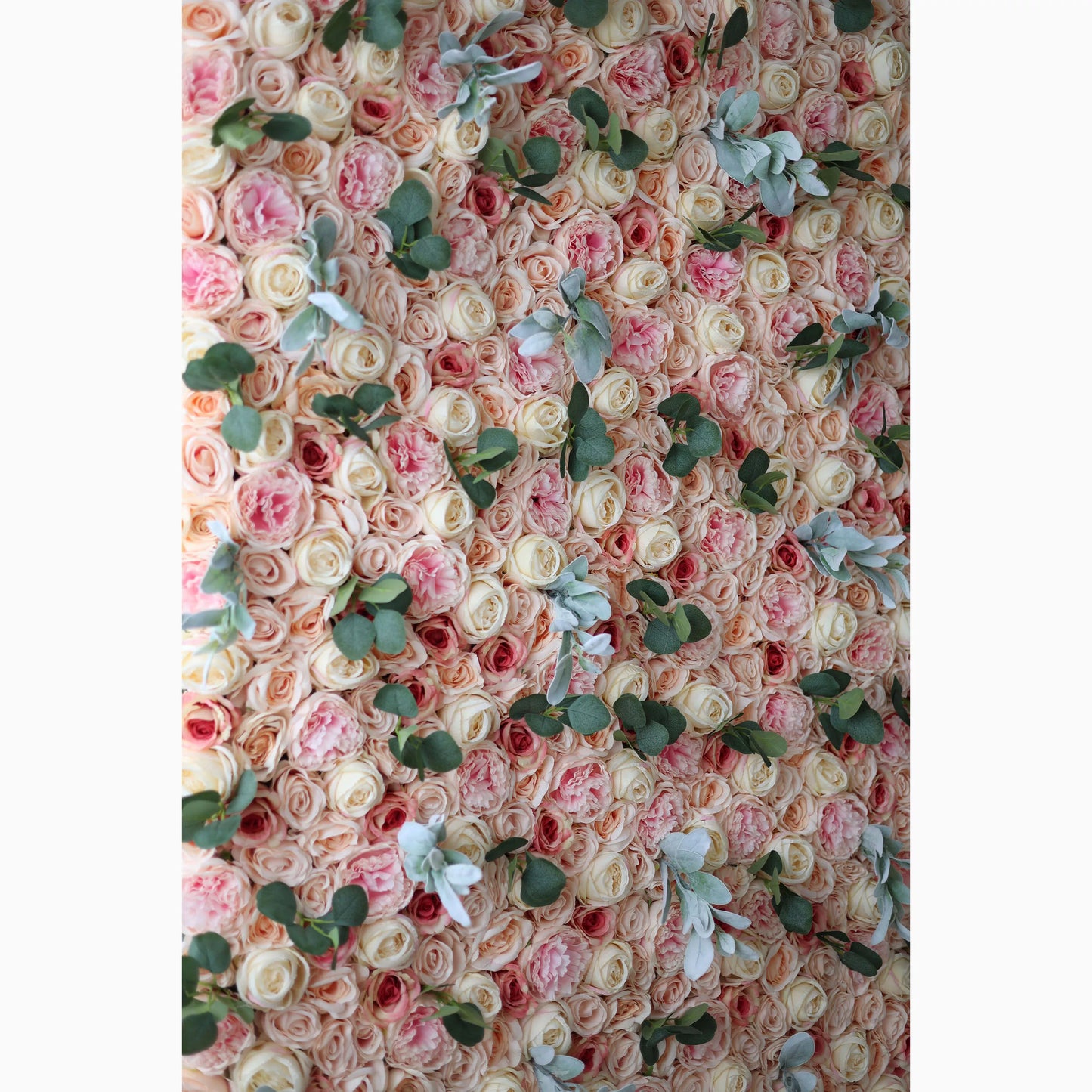 A large artificial flower wall features a harmonious mix of soft - pink, peach, and cream roses. Interspersed are green eucalyptus leaves and light - toned foliage, adding texture. The dense, layered arrangement creates a lush, romantic backdrop, ideal for adding elegance to events. 