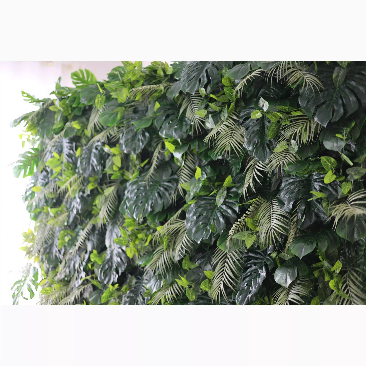 A large artificial greenery wall showcases a dense mix of lush leaves. Big monstera leaves and delicate fern - like fronds in various shades of green create a vibrant, tropical - inspired texture. It’s a fresh, natural - looking backdrop, perfect for adding an organic touch to decor or events. 