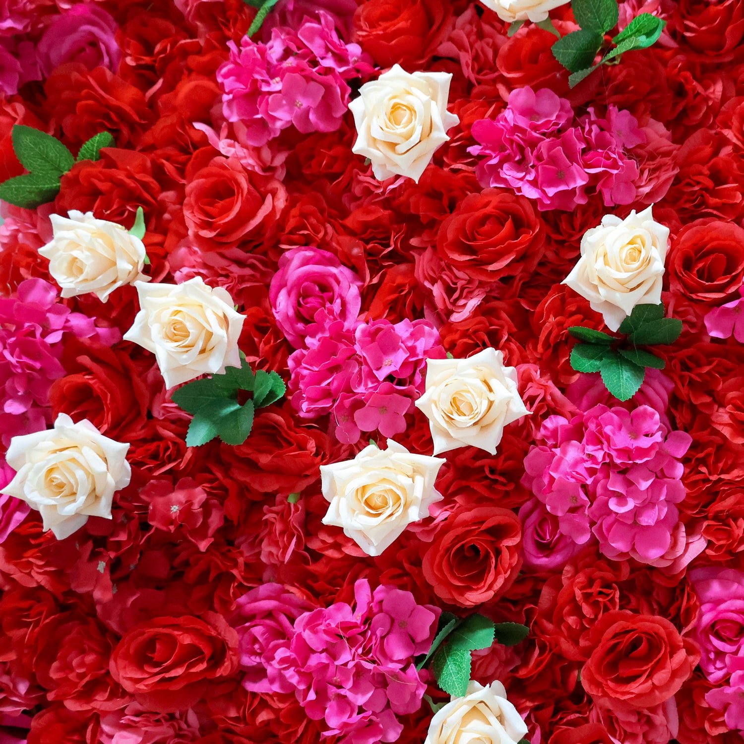 This close-up from Valar Flowers features a lush, vibrant floral arrangement. Creamy white roses stand out against a dense backdrop of deep red roses and bright pink hydrangeas, with green leaves adding contrast. The dense, layered design creates a rich, three-dimensional texture, evoking a bold, romantic, and naturally elegant atmosphere ideal for weddings, photo backdrops, or elegant celebrations.