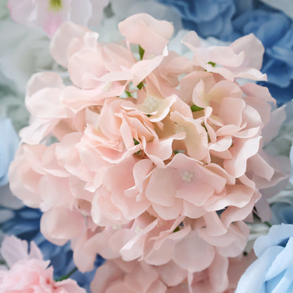 This close - up image showcases a cluster of artificial pink hydrangea flowers. The petals are soft and delicately layered, with a smooth texture that mimics real blooms. Surrounding the pink hydrangea are hints of blue and other pastel - colored flowers, creating a harmonious and charming floral arrangement. The overall scene exudes a sense of elegance and sweetness, perfect for decorative purposes in events or as part of a floral display.