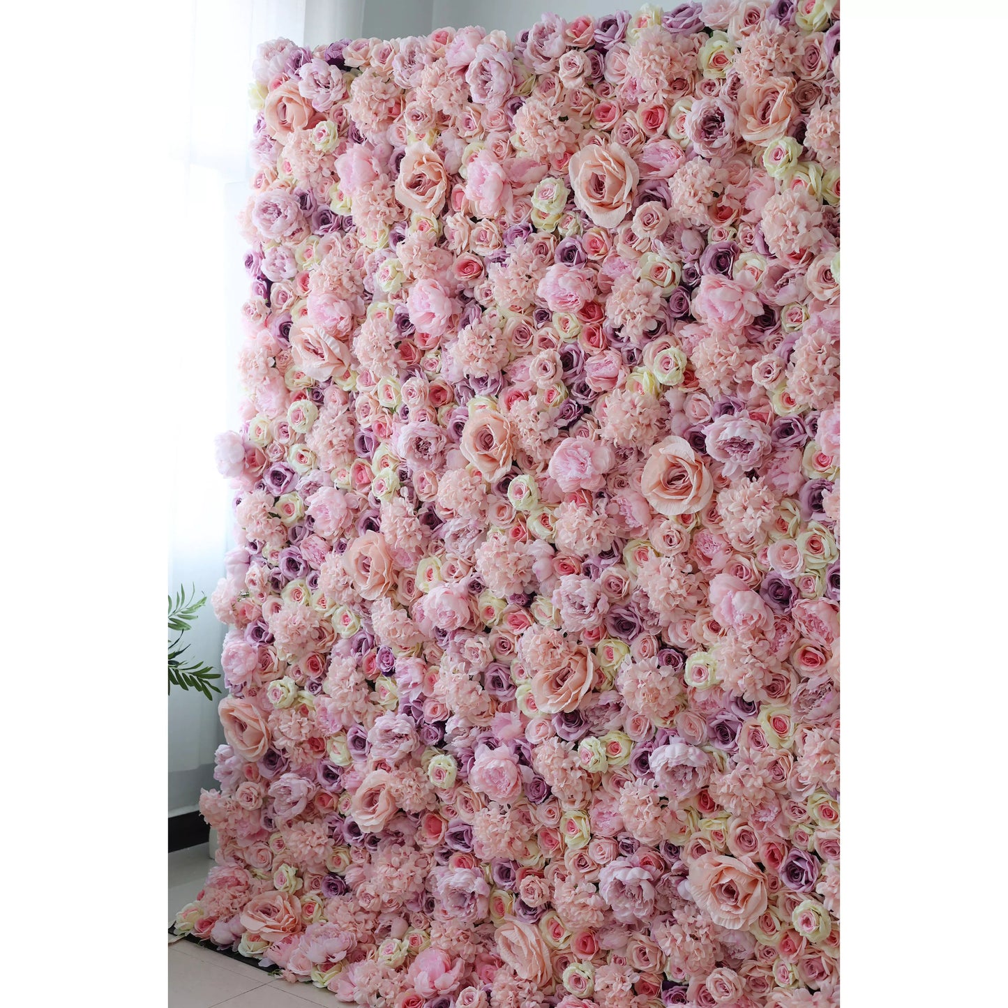 This indoor floral wall is a dense, immersive expanse of artificial blooms in soft blush pink, ivory, and subtle lavender tones, featuring layered roses and delicate filler flowers. The ruffled petals and varied textures create a dreamy, romantic surface, while the gentle gradient palette exudes timeless, feminine elegance. Ideal for weddings, photo booths, or upscale interiors, its artificial construction ensures long-lasting vibrancy and a flawless, consistent appearance.
