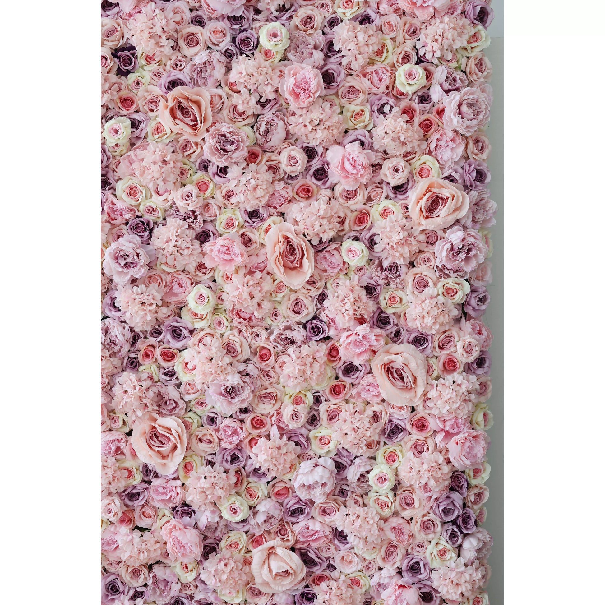 This lush, immersive floral wall is a dense arrangement of artificial blooms in a soft, romantic palette of blush pink, ivory, and subtle lavender. It features large, ruffled roses, delicate peonies, and clustered filler flowers, creating a rich, multi-textured surface. The gentle gradient of pastel tones and varied bloom sizes evoke a dreamy, timeless elegance, making it ideal for wedding backdrops, photo booths, or upscale interiors seeking a feminine, romantic focal point.