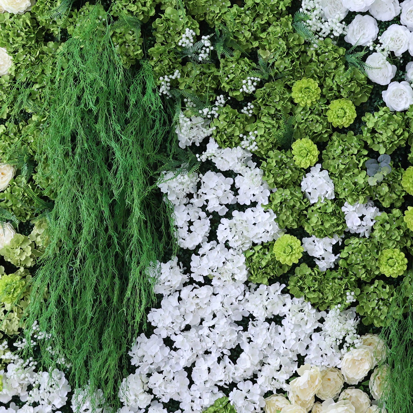 This image showcases a lush artificial floral wall. It features a dense arrangement of various green foliage, including trailing vines, alongside abundant white flowers like hydrangeas and small accent blooms. The combination creates a vibrant, natural - looking display with a harmonious blend of green and white, exuding freshness and elegance. Perfect for decorative purposes in events or as an interior backdrop, it blends artistry with a touch of nature's charm.