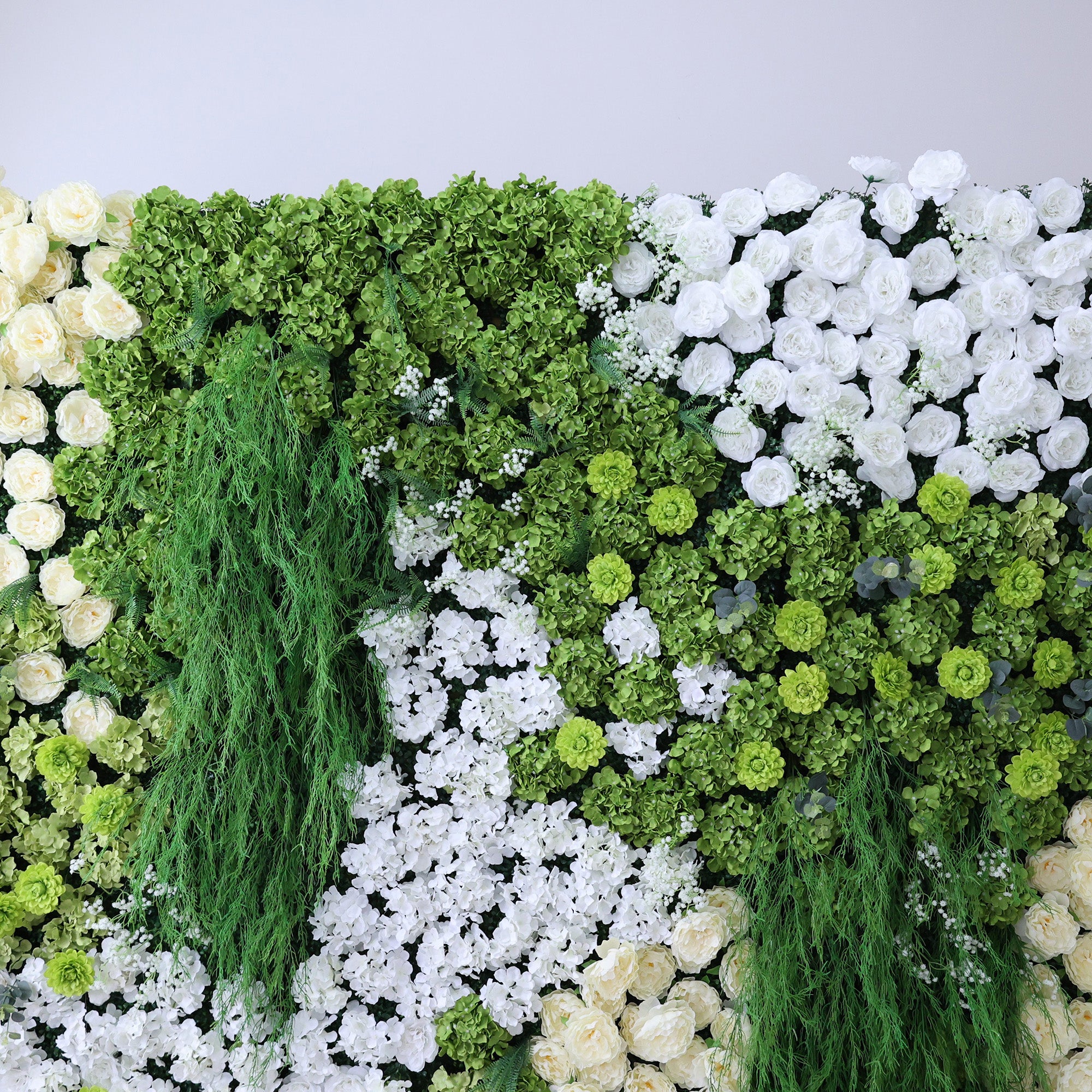 This image showcases a lush artificial floral wall. It features a dense arrangement of various flowers, including abundant white roses, creamy - hued blooms, and assorted white and green foliage. Trailing green vines add a natural touch. The harmonious blend of white, cream, and green creates a vibrant, elegant, and refreshing display, perfect for decorative purposes in events or as an interior backdrop, exuding a sense of natural beauty and artistry.