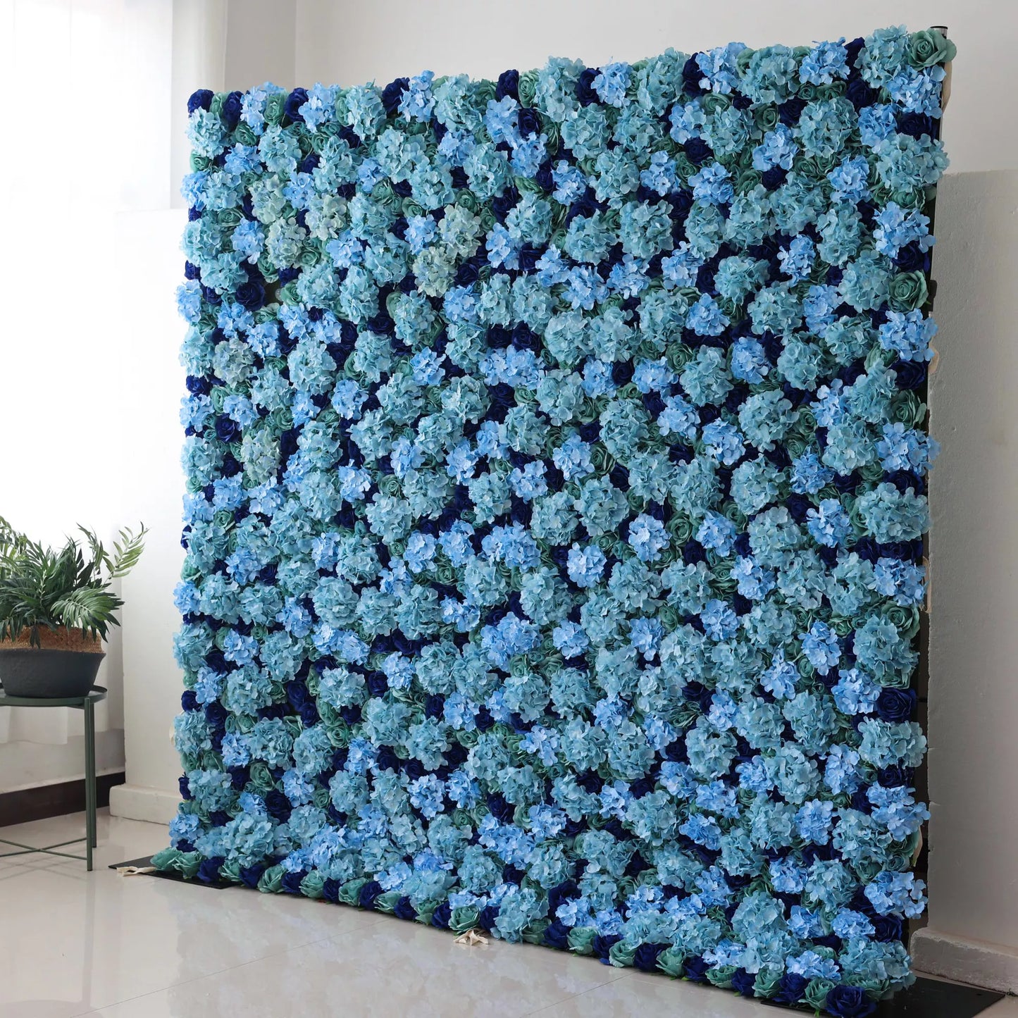 Valar Flowers' Azure Blossom: A large artificial flower wall showcases dense, layered blue hydrangeas in varying shades, from light sky to deep navy, with hints of green foliage. The rich, harmonious color palette creates a serene, elegant backdrop, perfect for adding a touch of refined beauty to events or decor.