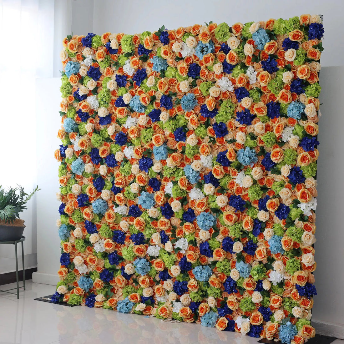 Valar Flowers Roll Up Backdrop: This large artificial flower wall is a vibrant, colorful display. It features a mix of orange roses, blue blossoms, white flowers, and green foliage, densely arranged to create a lush, textured look. The harmonious blend of colors evokes a cheerful, lively atmosphere, making it perfect as a backdrop for events like weddings, parties, or photo shoots, adding an eye - catching and decorative touch.