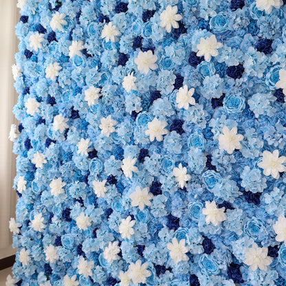 A close - up of a large artificial flower wall features blue hydrangeas, white daisy - like blooms, and dark blue blossoms. The dense, uniform arrangement creates a serene, elegant backdrop, perfect for events, evoking a calm and sophisticated vibe. 