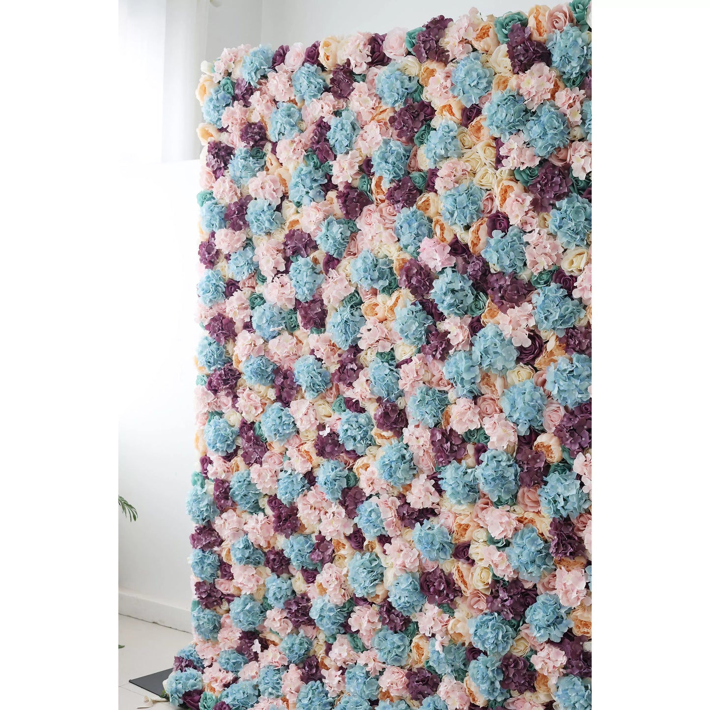 This large artificial flower wall is a vibrant tapestry of pastel hues—soft pinks, blues, purples, and creams. Densely packed with diverse blooms like hydrangeas and roses, it creates a lush, textured display. Ideal for event backdrops, it adds an elegant, colorful touch to weddings or parties, enhancing the decorative appeal of any space. 