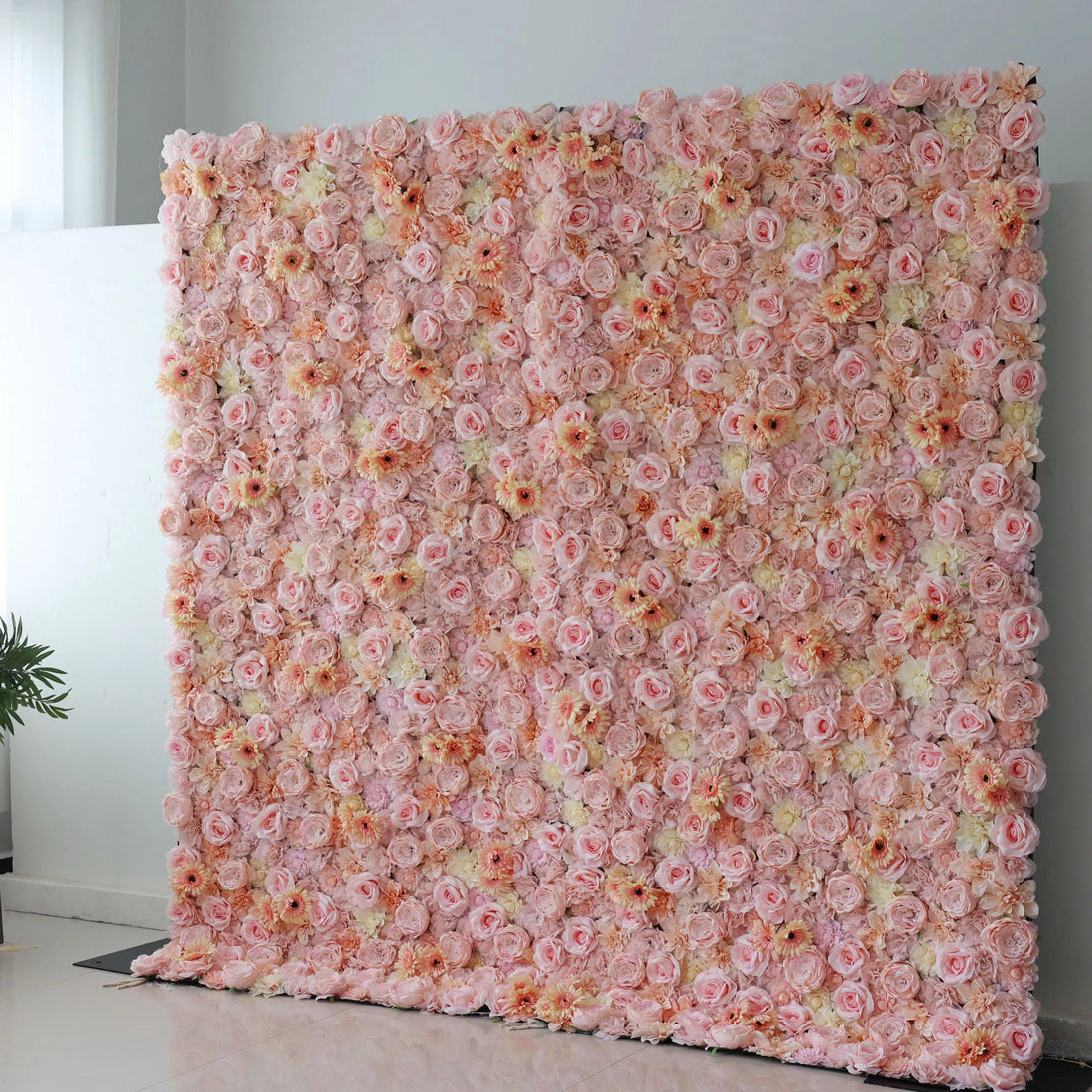 This picture showcases a large artificial flower wall, a beautiful blend of soft pink, peach, and cream tones. It’s densely packed with an array of blooms, including roses and daisy - like flowers, creating a lush, romantic display. The varied textures and pastel colors make it perfect for event backdrops, adding an elegant and charming touch to any space, ideal for weddings or parties to create a dreamy atmosphere.