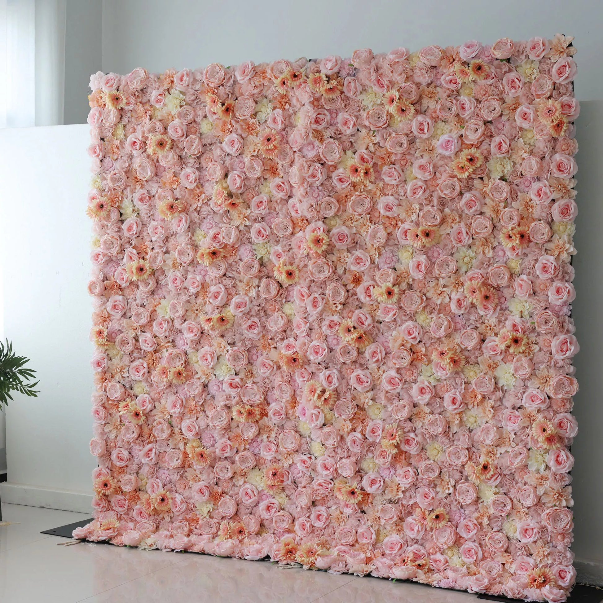 This picture showcases a large artificial flower wall, a beautiful blend of soft pink, peach, and cream tones. It’s densely packed with an array of blooms, including roses and daisy - like flowers, creating a lush, romantic display. The varied textures and pastel colors make it perfect for event backdrops, adding an elegant and charming touch to any space, ideal for weddings or parties to create a dreamy atmosphere. 