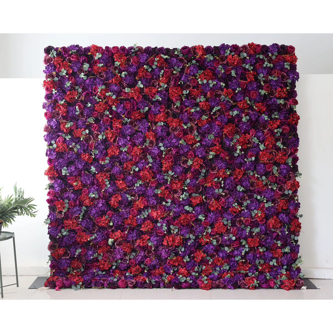 Valar Flowers Roll Up Backdrop: This picture shows a large artificial flower wall, densely packed with flowers in rich hues of purple and red. Interspersed among the blooms are small green eucalyptus - like leaves, adding a touch of contrast. The vibrant and lush arrangement makes it an ideal decorative element for events, creating a dramatic and romantic backdrop.