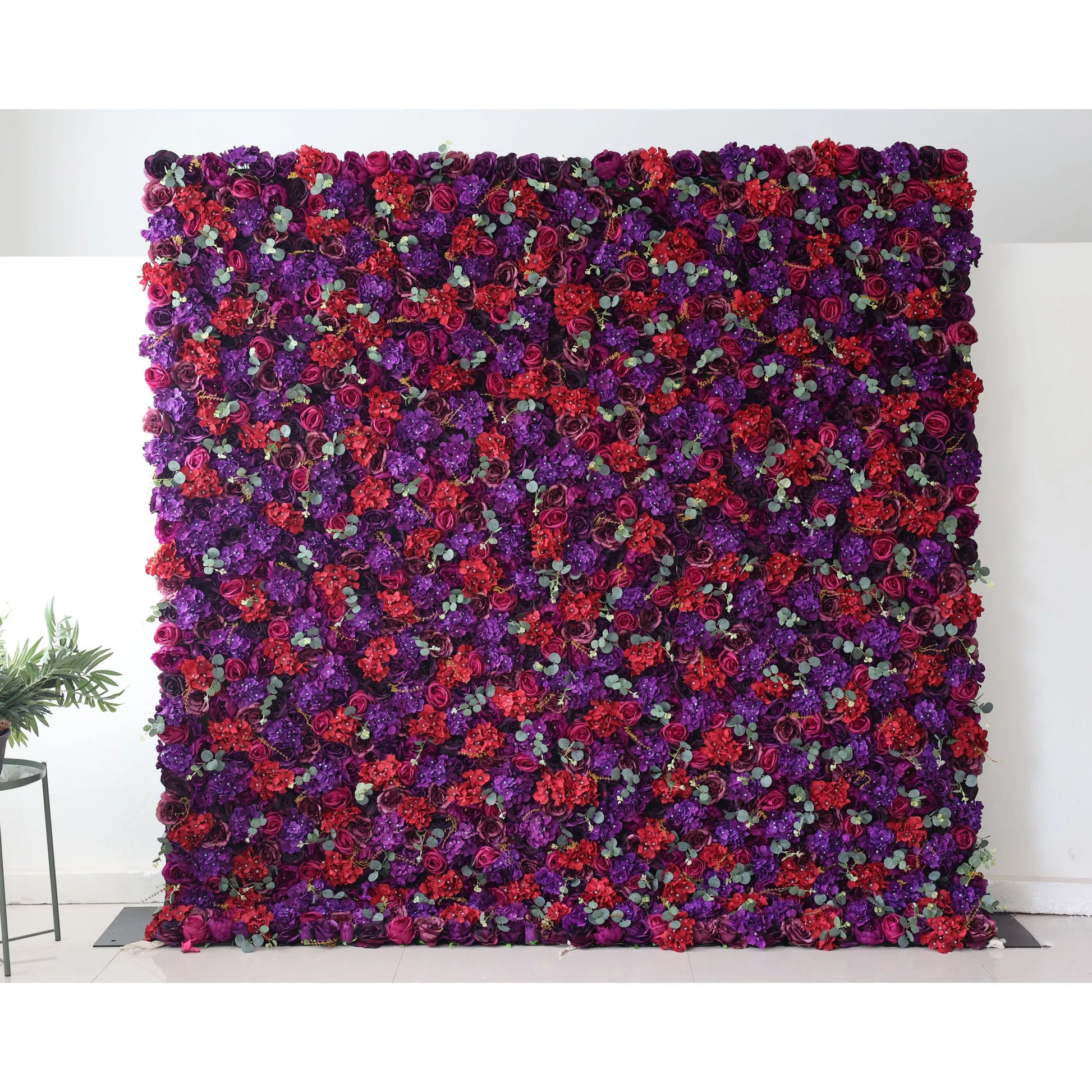 Valar Flowers Roll Up Backdrop: This picture shows a large artificial flower wall, densely packed with flowers in rich hues of purple and red. Interspersed among the blooms are small green eucalyptus - like leaves, adding a touch of contrast. The vibrant and lush arrangement makes it an ideal decorative element for events, creating a dramatic and romantic backdrop. 