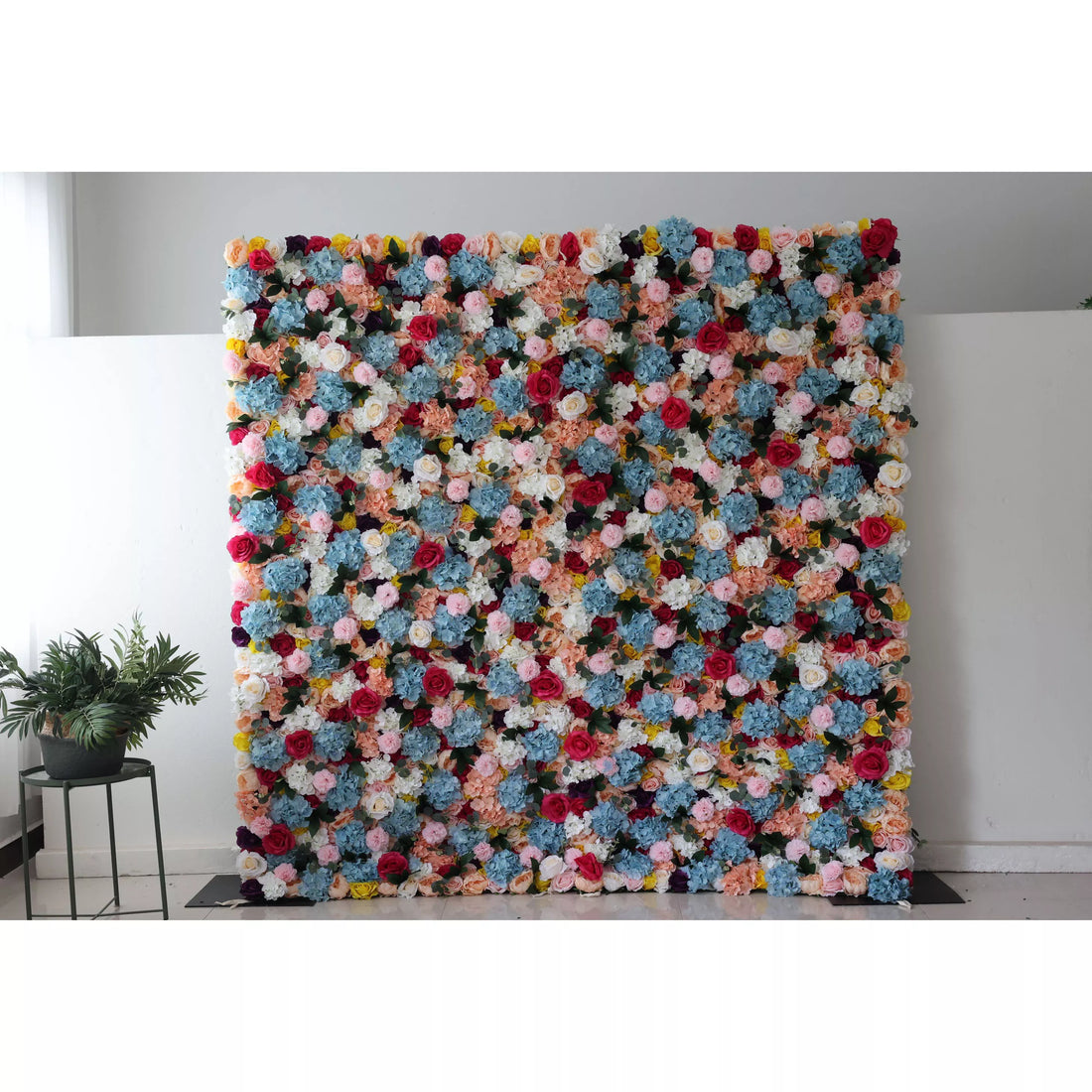This is a large, vibrant artificial flower wall. It features a dense mix of colors—blue, pink, white, yellow, and red blooms. The varied flowers create a lively, eye - catching display, perfect for event backdrops, adding a cheerful and decorative touch to spaces.