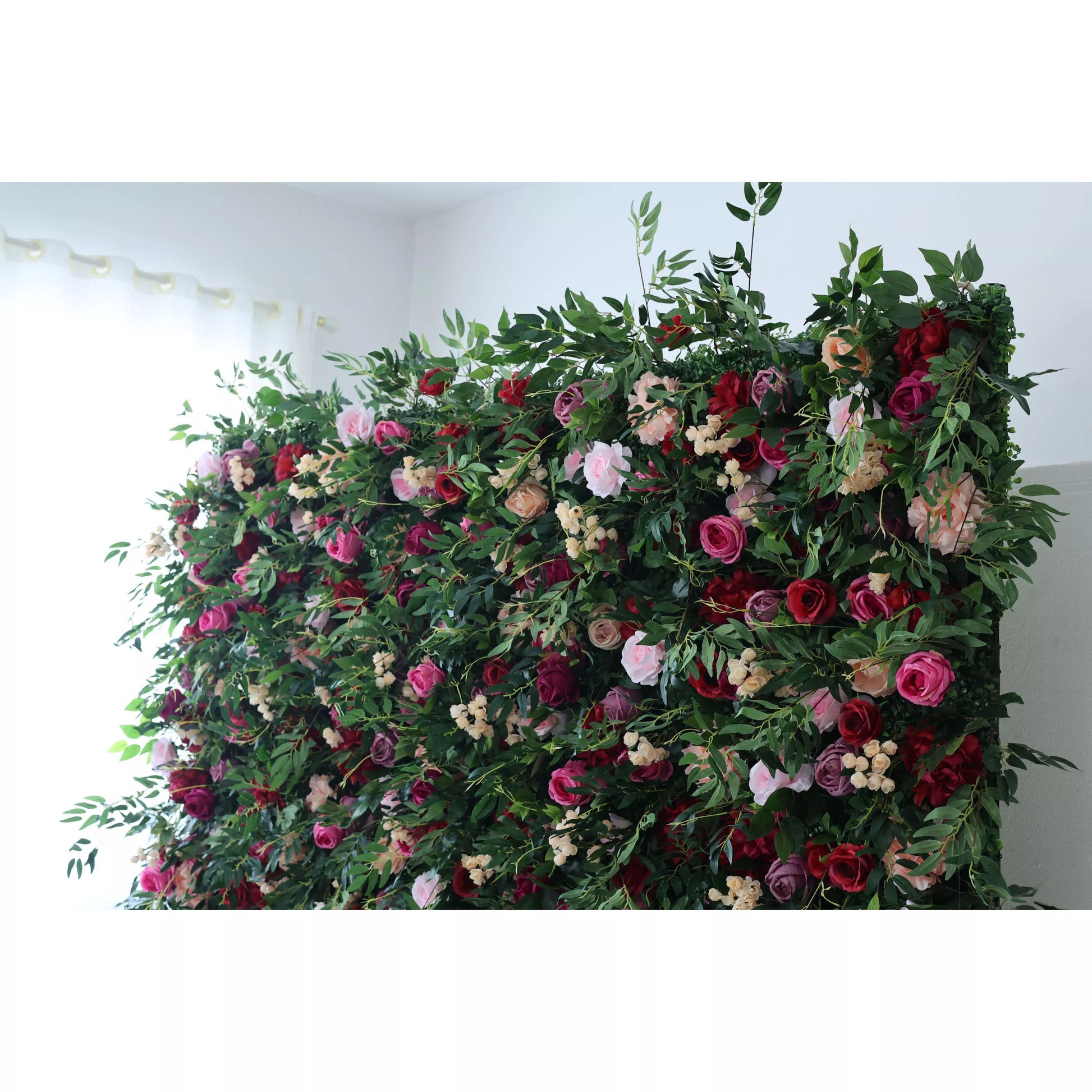 A lush artificial flower wall features a vibrant mix of pink, red, purple roses, and peach blooms, intertwined with green foliage and small white flowers. It creates a romantic, natural - looking backdrop, ideal for events or decorative spaces, adding a touch of elegance and charm. 