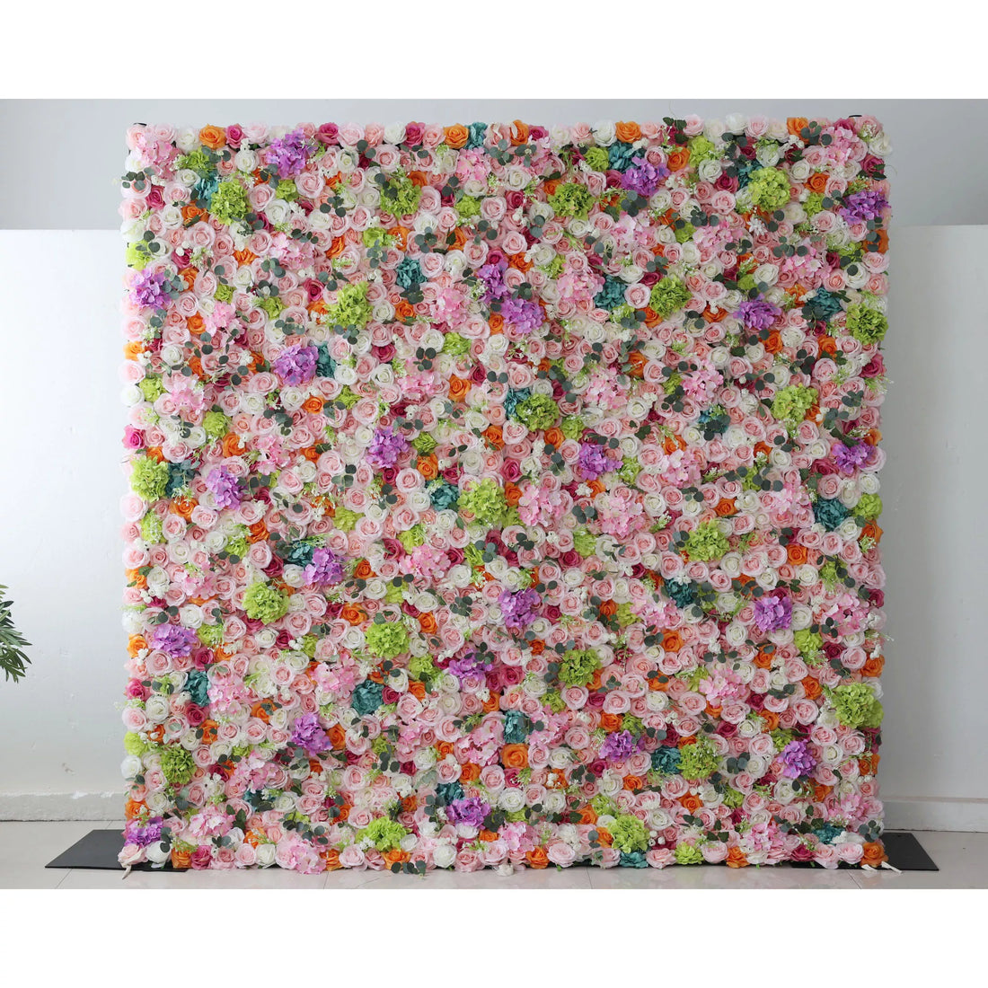 This flower wall is a vibrant, dense display of artificial blooms. A harmonious mix of colors—white, pink, purple, orange, and green—creates a lively, celebratory feel. Varied flower types and textures add depth, making it perfect for events like weddings or parties, exuding joy and elegance.