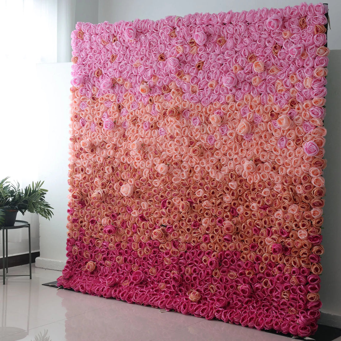 This picture features a large artificial flower wall, a gradient of pink hues. It&