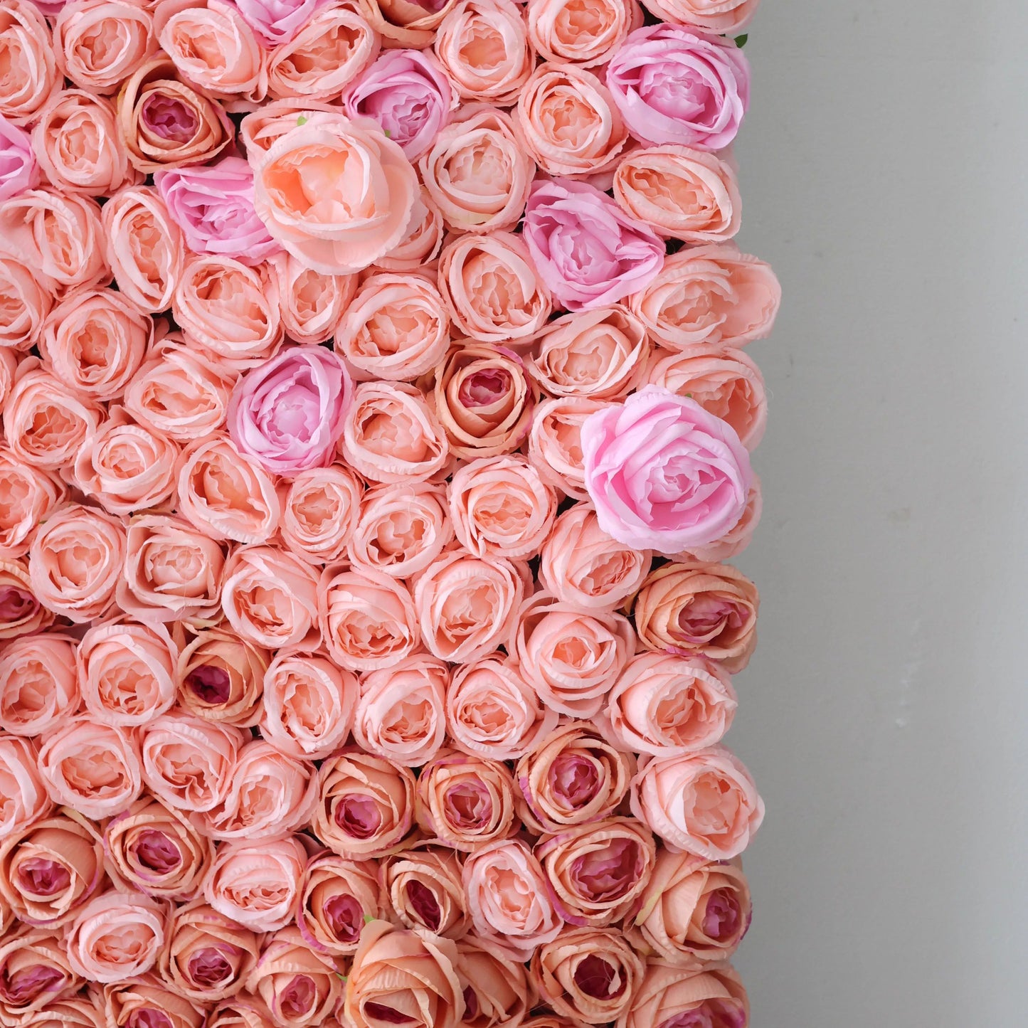 This close - up shows a section of an artificial flower wall. It's densely packed with peach - colored roses, interspersed with a few soft pink blooms. The uniform, lifelike petals create a romantic, visually appealing texture. Ideal for decorative backdrops, adding a sweet and elegant touch to events or spaces, evoking a sense of delicate beauty. 