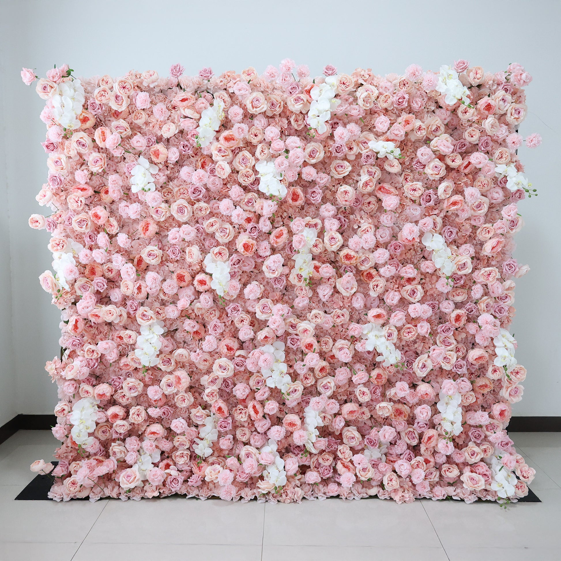 This is a stunning flower wall crafted by Valar Flowers. It's a large, square arrangement brimming with an abundance of pink roses and interspersed with delicate white blooms. The flowers are densely packed, creating a lush and vibrant display. Set against a plain white wall and placed on a light - colored tiled floor, the flower wall stands out beautifully, exuding a romantic and elegant charm, perfect for adding a touch of beauty to various events or spaces.