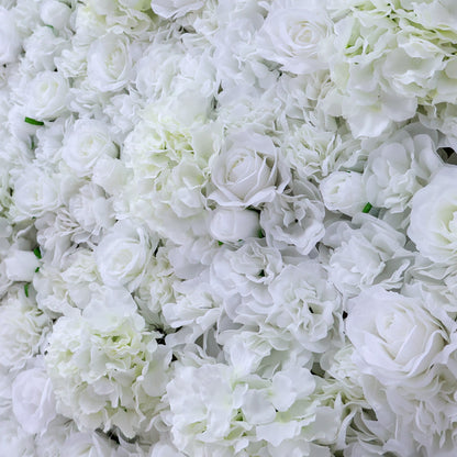 A dense wall of artificial white flowers, featuring various blooms like roses and hydrangeas, creates a lush, elegant display. The pure white hues and abundant arrangement give off a romantic, sophisticated vibe, perfect for events such as weddings, bridal showers, or upscale parties needing a beautiful backdrop.