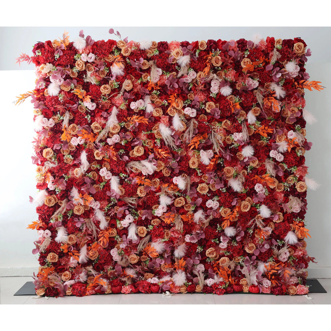 This flower wall is a striking composition, densely packed with a variety of artificial flowers. The dominant red hues blend with accents of pink, orange, and touches of white fluffy elements and foliage. The rich color palette and diverse textures create a warm, passionate atmosphere, making it an ideal backdrop for weddings, events, or photo - shoots, exuding both elegance and a sense of grandeur.