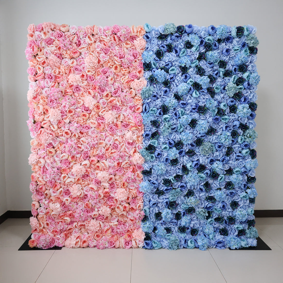This image showcases a dual-toned floral backdrop by ValarFlowers, set indoors. It features dense artificial flowers—soft pinks and peaches on one side, varied blues on the other. The lush, textured display exudes elegance, perfect for adding a luxurious, nature-inspired element to events or interiors.
