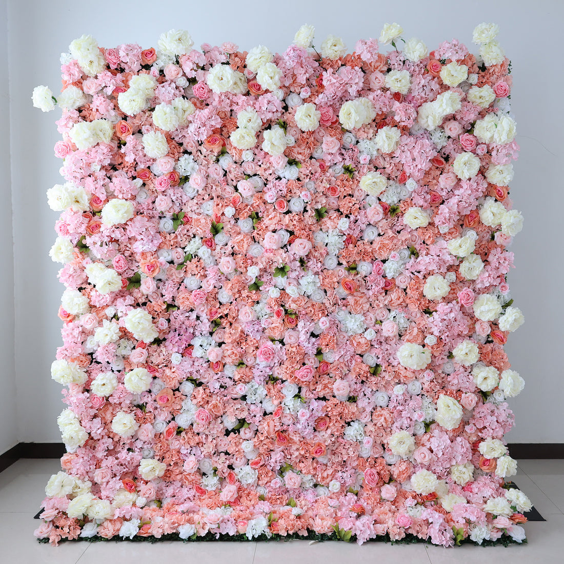 This image showcases a lush artificial floral backdrop with a vibrant mix of pink, peach, and white flowers, including roses and hydrangeas. The dense, textured arrangement creates a luxurious, nature-inspired display, ideal for adding elegance and sophistication to events or interiors.